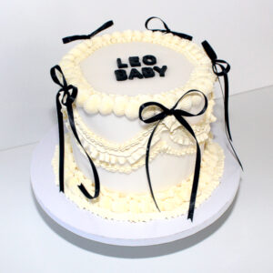 Elegante weisse Torte mit Fondant, Buttercreme und schwarzen Schleifen für Feste